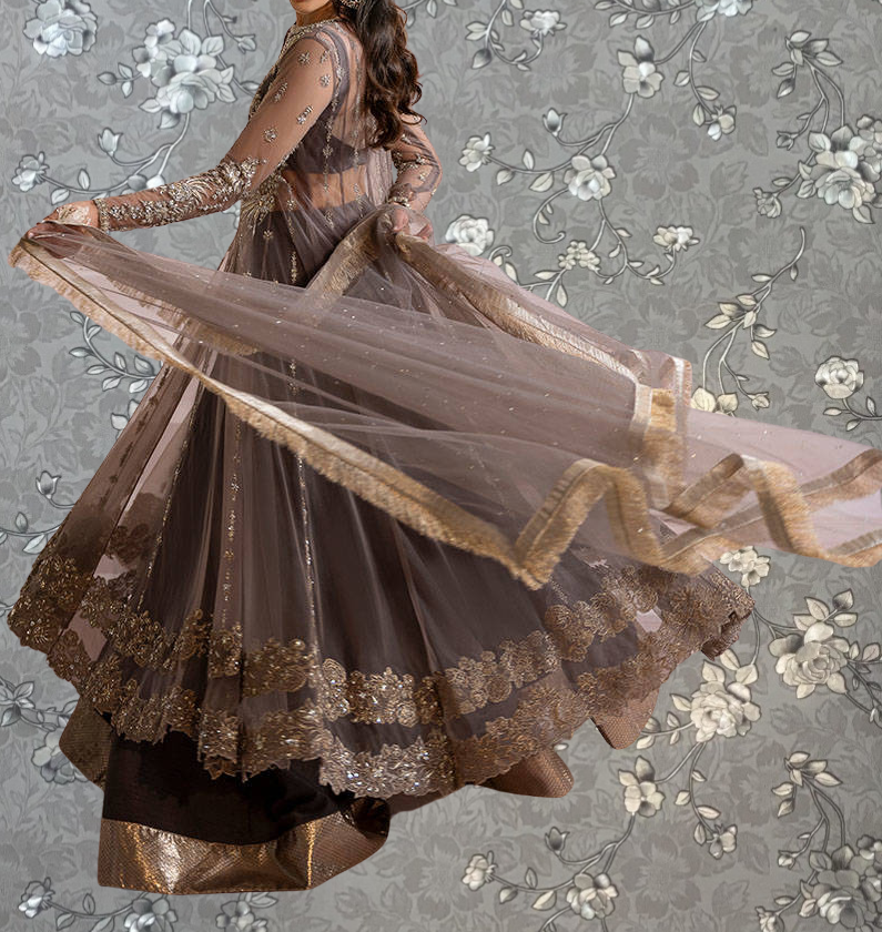 A woman wearing a brown and gold dress with a flowing skirt is shown against a gray floral background.