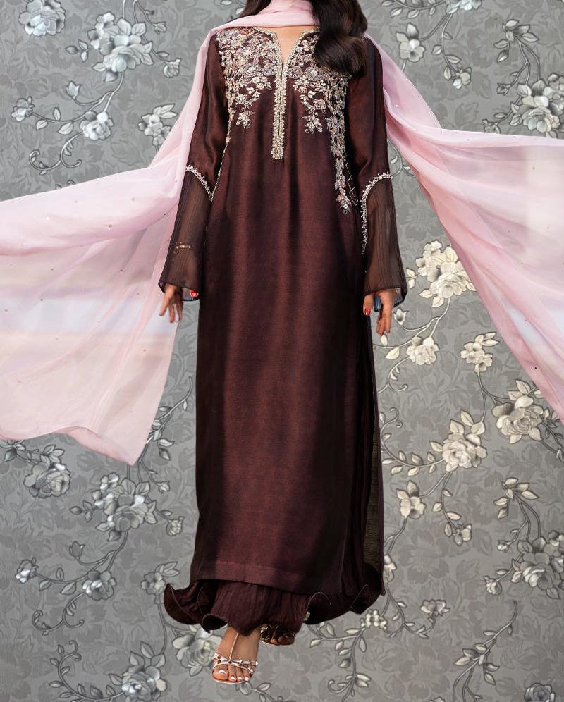 A woman wearing a long, burgundy-colored dress with intricate embroidery and a matching pink shawl.