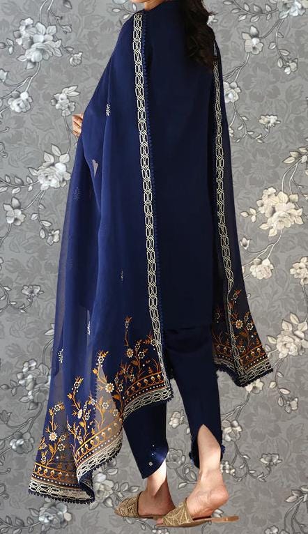 A person wearing a navy blue dress with gold floral embroidery on the sleeves and a matching shawl.