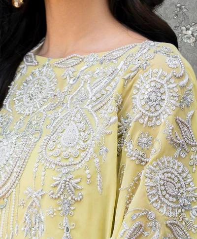 a close-up view of a woman's neck and chest area wearing a yellow dress with intricate white embroidery.