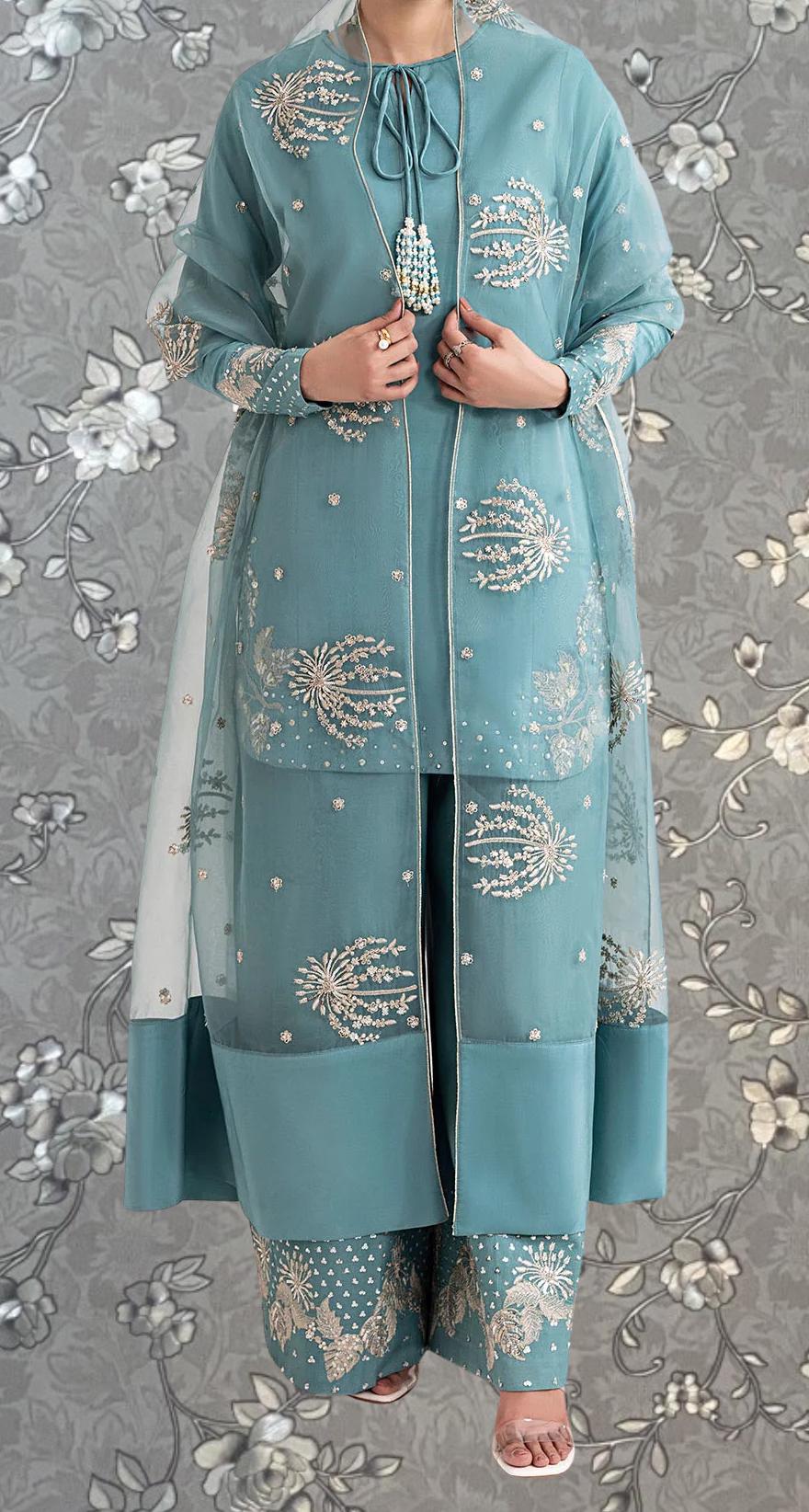A person wearing a long, light blue dress with intricate embroidered patterns and a matching jacket.