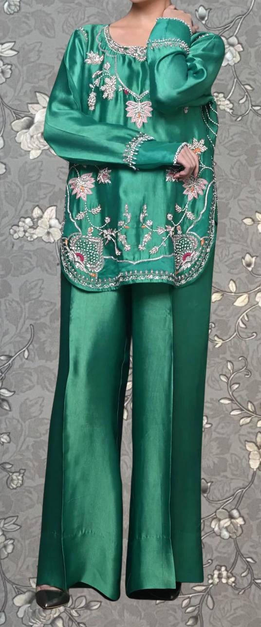 A person wearing a green dress with intricate embroidery and floral patterns.