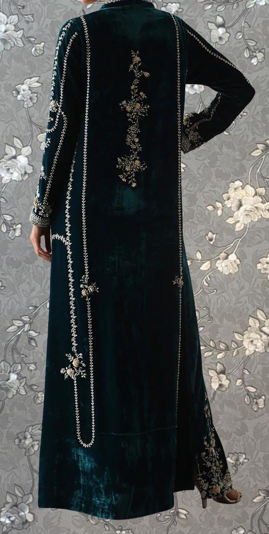 a person wearing a long, dark green velvet coat with intricate embroidered designs on the back.