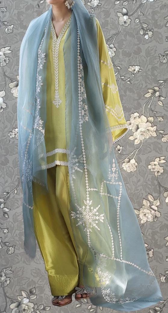 A person wearing a yellow and blue dress with a long, flowing blue shawl draped over their shoulders.