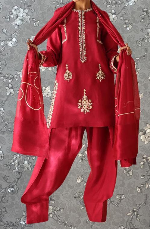 A person wearing a red and gold traditional Indian outfit, including a red and gold embroidered dress and matching red and gold shawl.