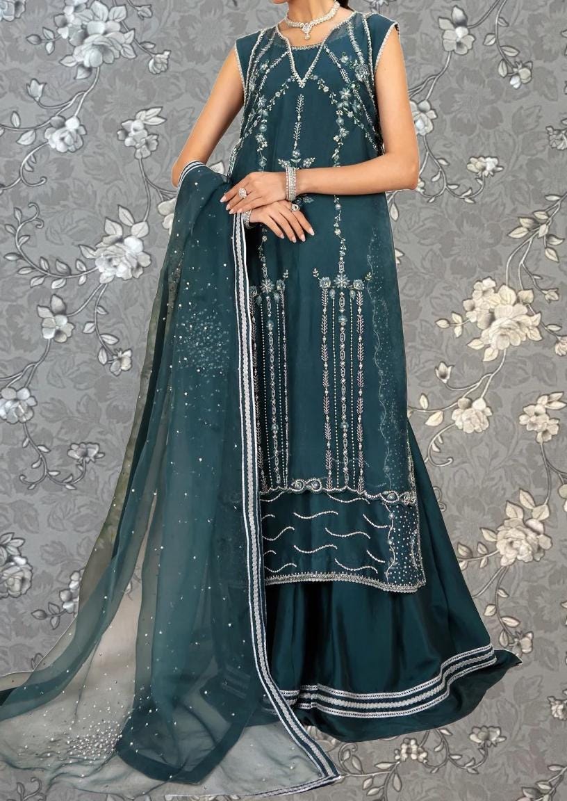 A woman wearing a long, sleeveless green dress with intricate embroidery and a matching green shawl.