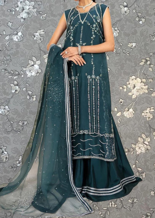A woman wearing a long, sleeveless green dress with intricate embroidery and a matching green shawl.