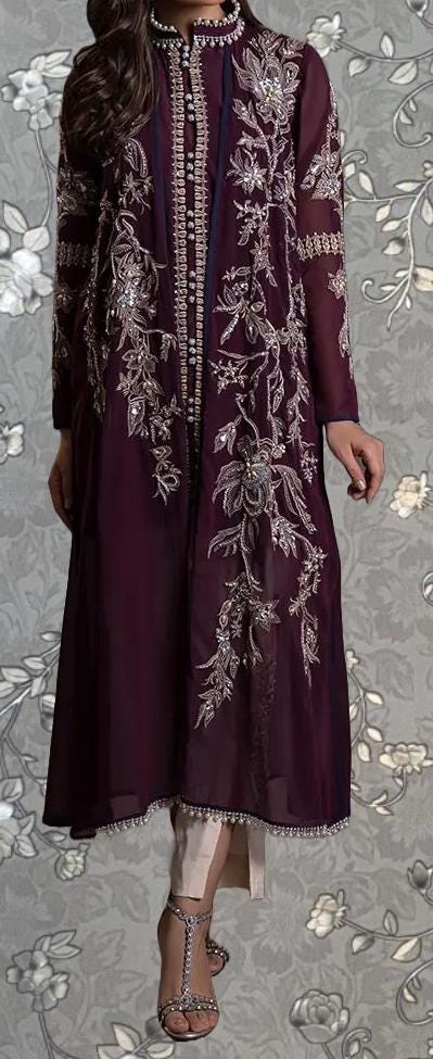 A woman wearing a long, burgundy dress with intricate embroidery and floral patterns.