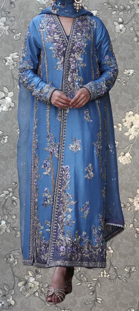 A person wearing a long, blue dress with intricate embroidery and floral patterns.