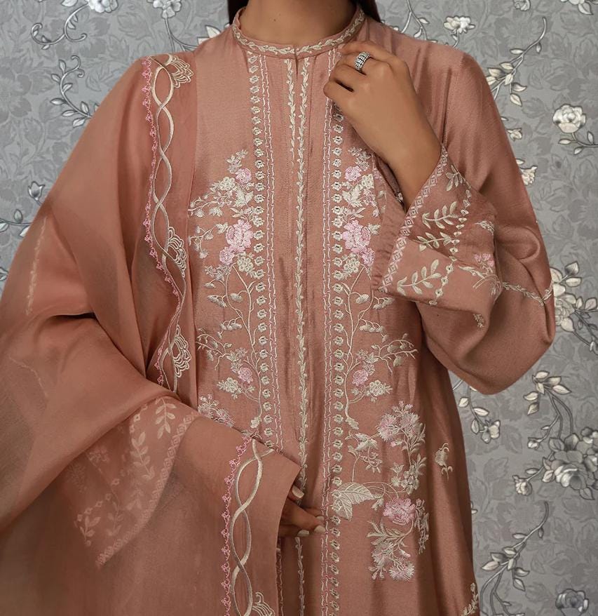 A woman wearing a pink and white floral dress stands against a gray floral background.