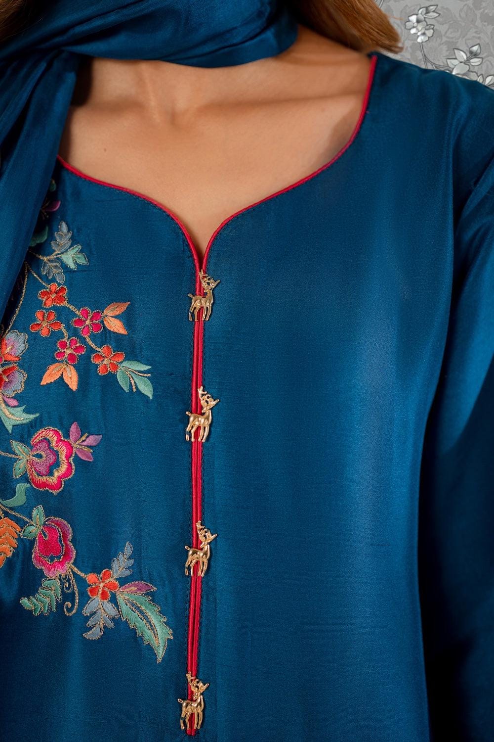 A close-up view of a woman wearing a blue dress with a floral pattern and decorative elements.