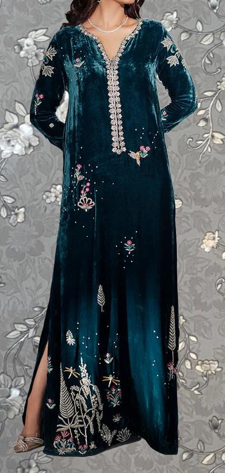 A woman wearing a long, green velvet dress with intricate embroidered designs.