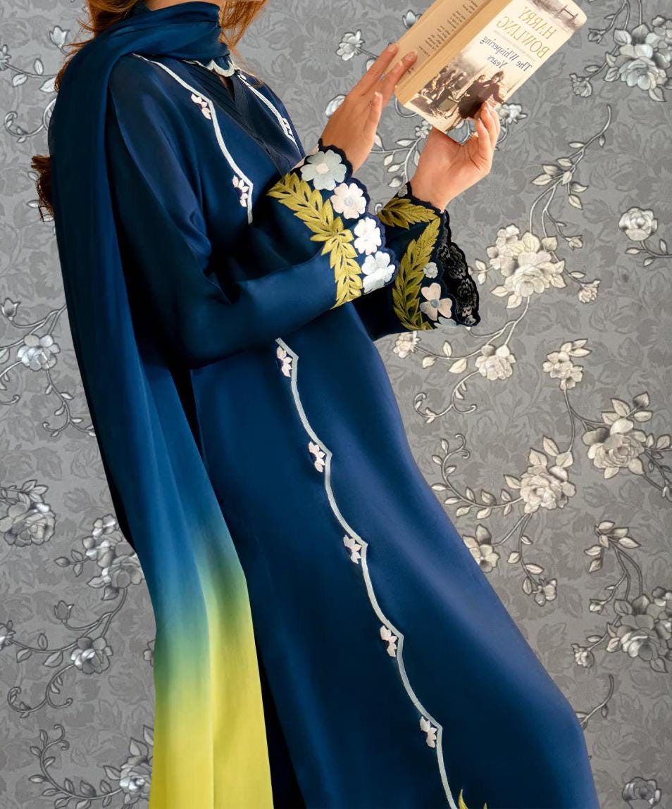 A person wearing a blue and yellow dress with gold embroidery is holding a book and appears to be reading.