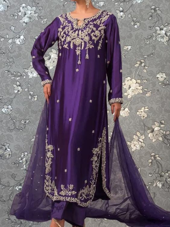 A woman wearing a long purple dress with intricate embroidery and a matching purple shawl.