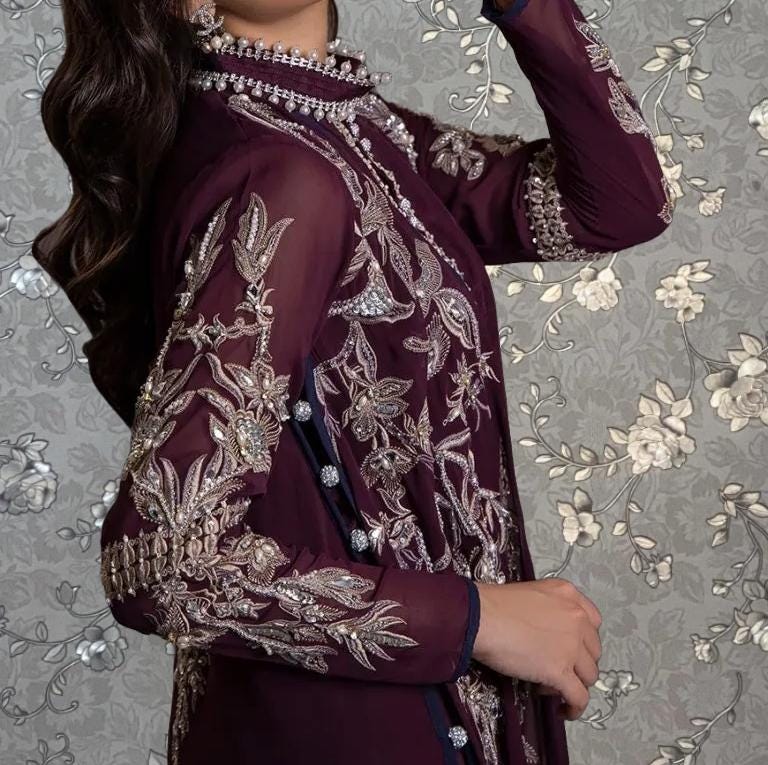 A close-up of a woman wearing a burgundy dress with intricate embroidery and floral patterns.