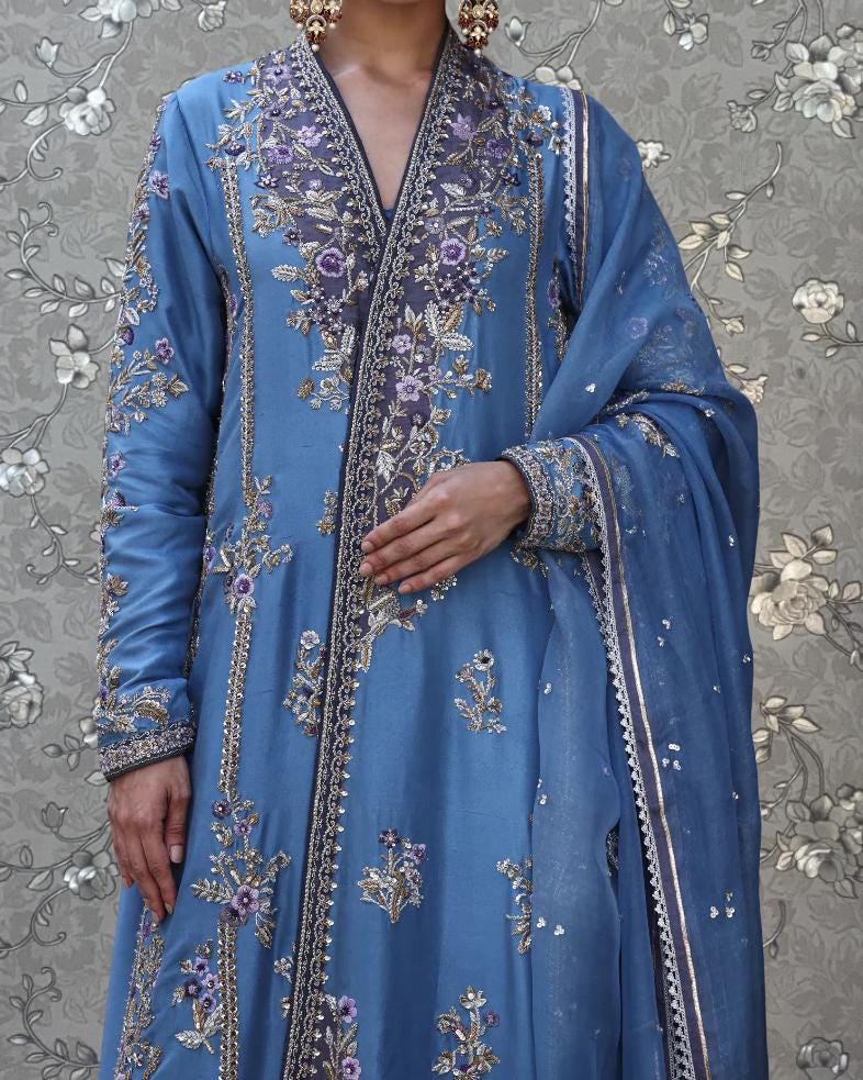 A person wearing a blue and gold embroidered dress with a matching shawl.