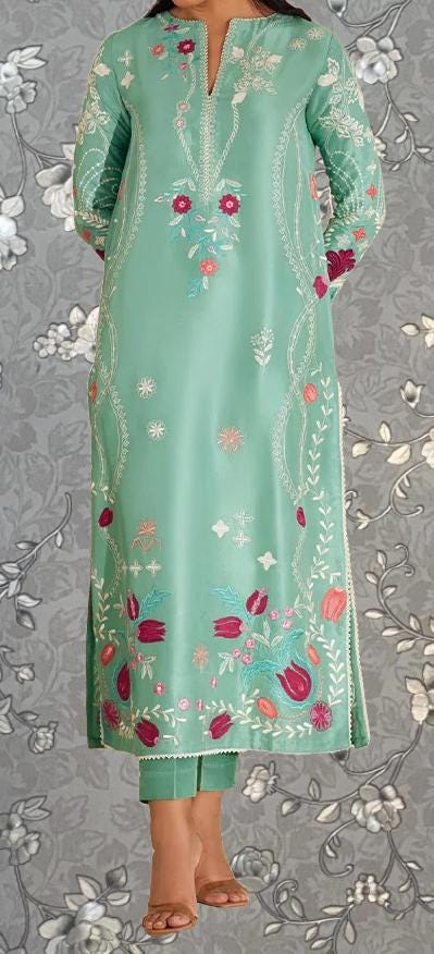 A woman wearing a long, mint green dress with intricate floral embroidery on the front.
