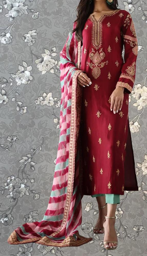 A woman wearing a red and gold embroidered dress with a long, flowing skirt and a matching shawl.