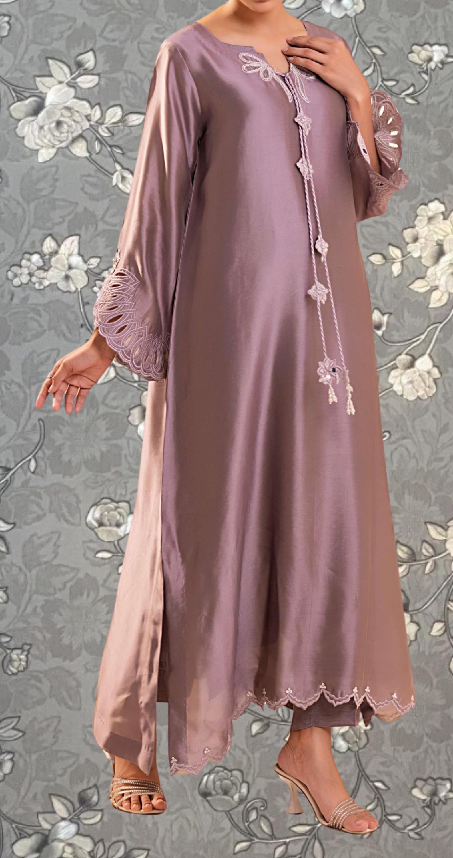 A woman wearing a long, purple dress with lace detailing and a floral pattern on the background.