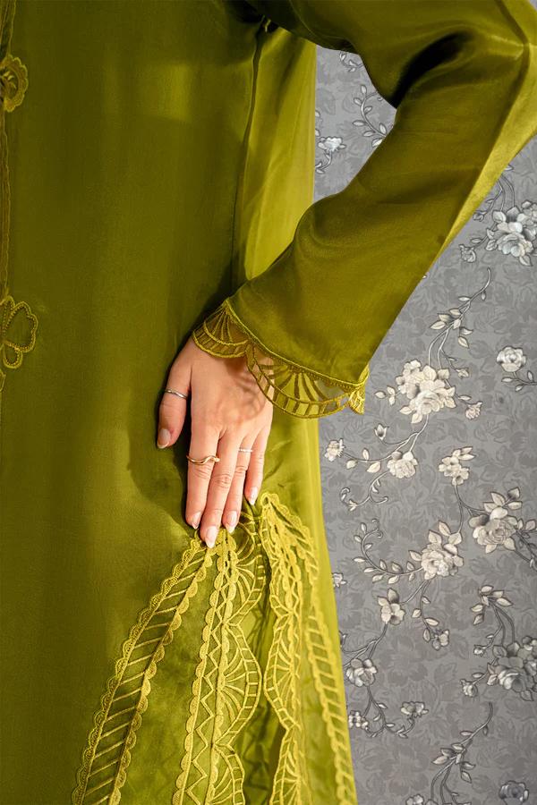A close-up view of a hand wearing a green dress with intricate embroidery and lace details.