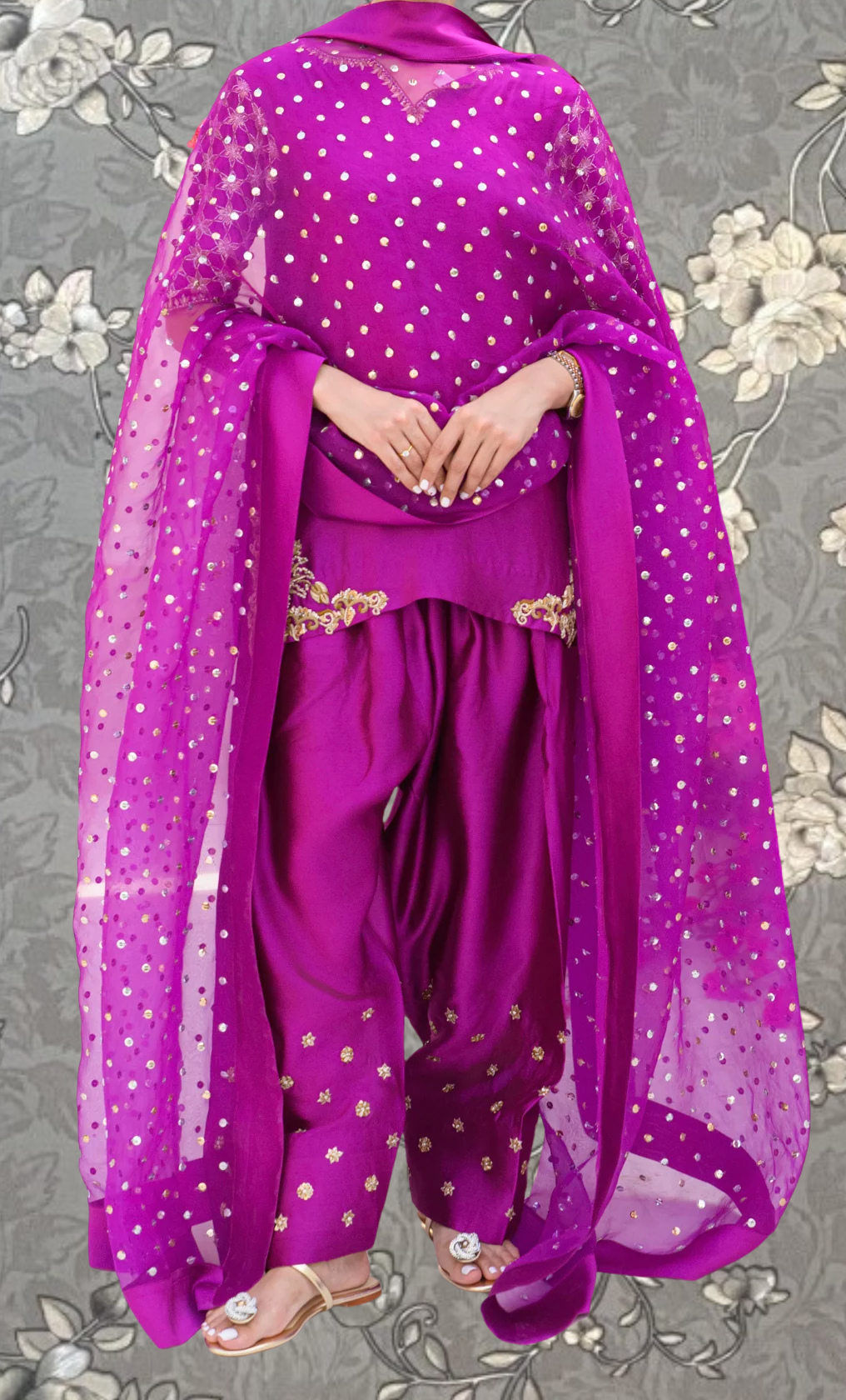 A person wearing a vibrant purple outfit with a sheer, polka-dotted fabric draped over their body.