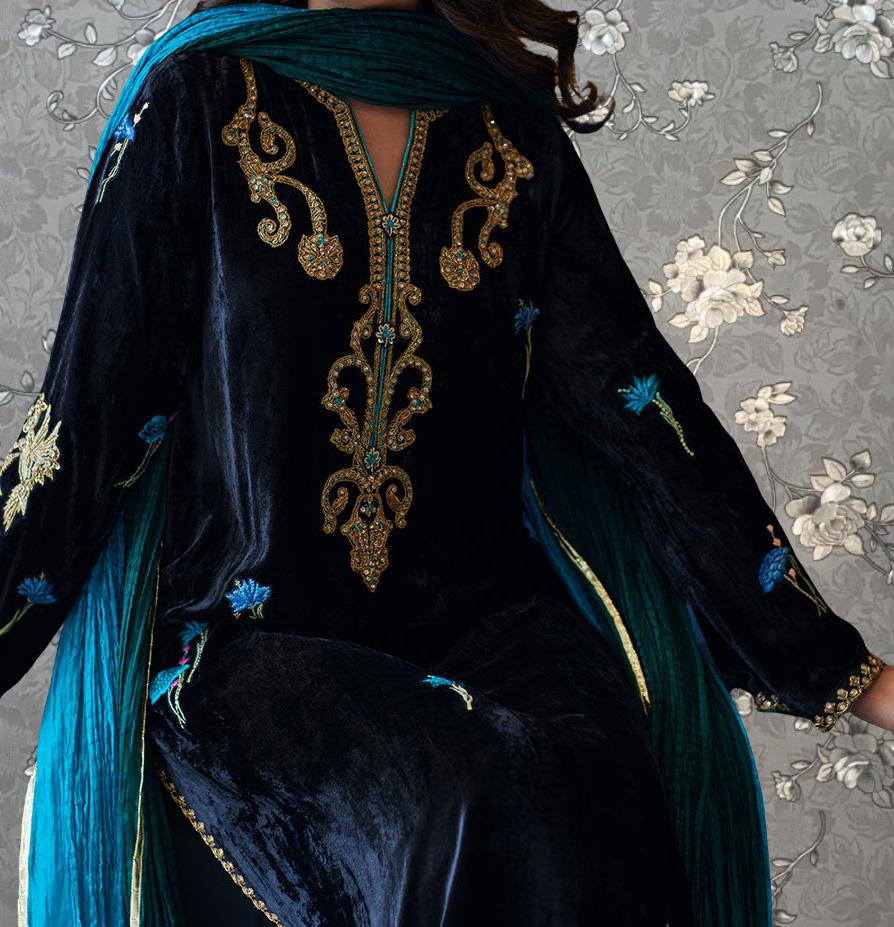 A close-up of a person wearing a black velvet dress with intricate gold embroidery and blue accents, including a matching blue and green shawl draped over the shoulders.