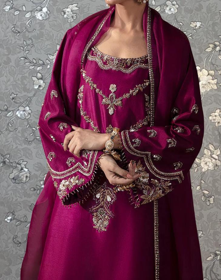 A woman wearing a vibrant purple dress with intricate embroidery and jewelry poses against a floral background.