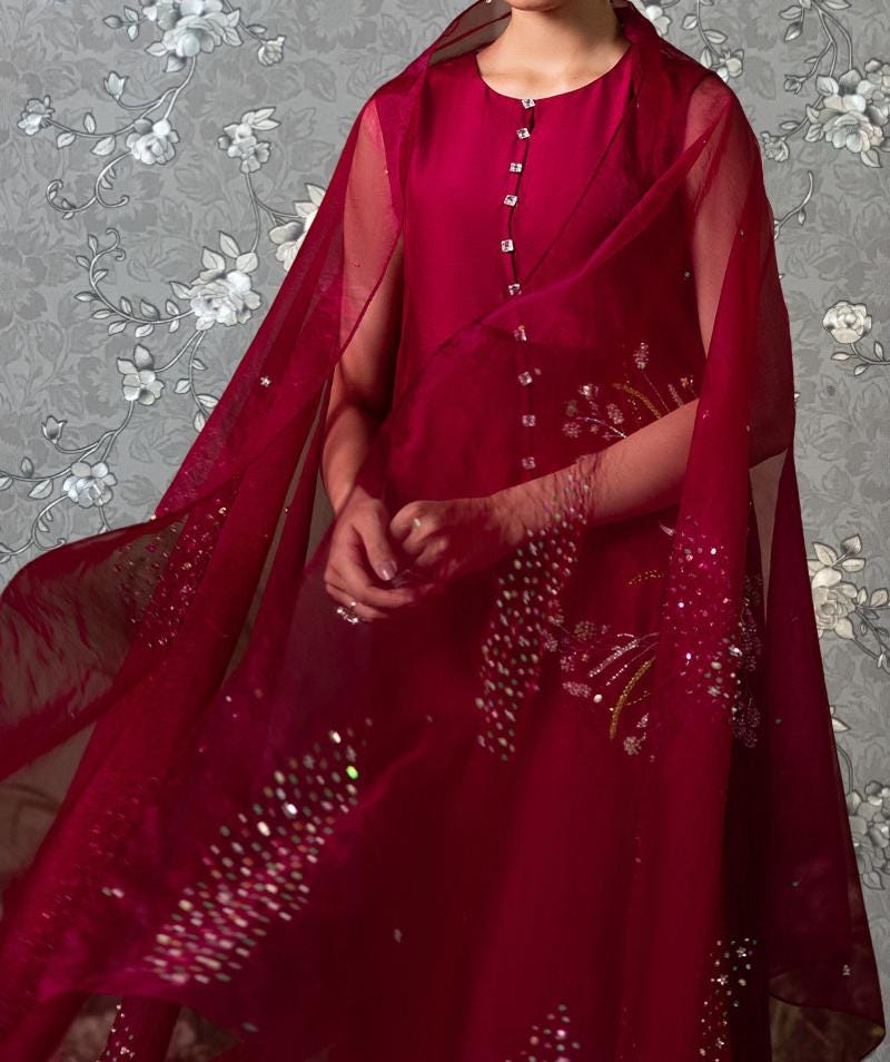 A person wearing a red dress with a sheer, flowing skirt and a matching red cape.