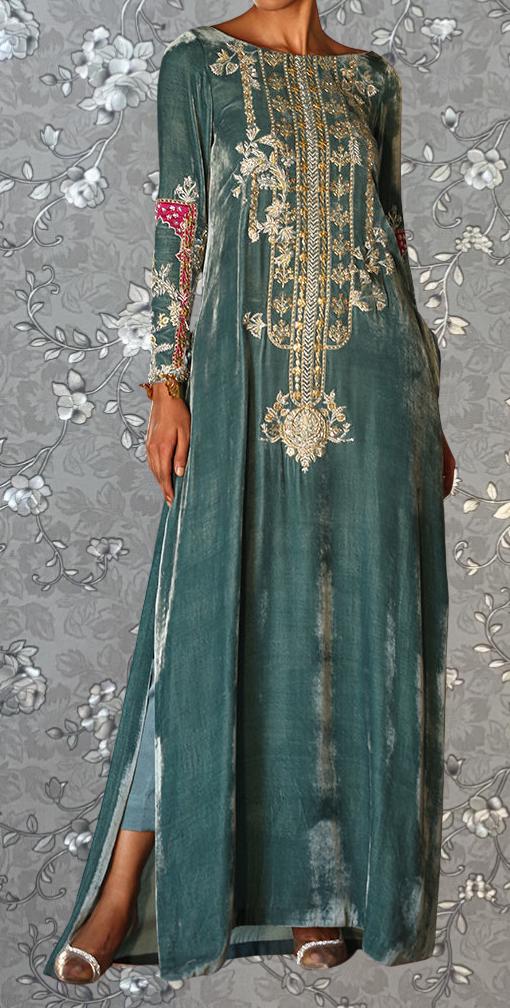 A woman wearing a long, green dress with intricate gold embroidery and floral patterns.