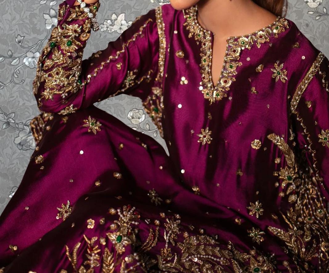 a close-up view of a woman wearing a long, purple dress with intricate gold embroidery and embellishments.