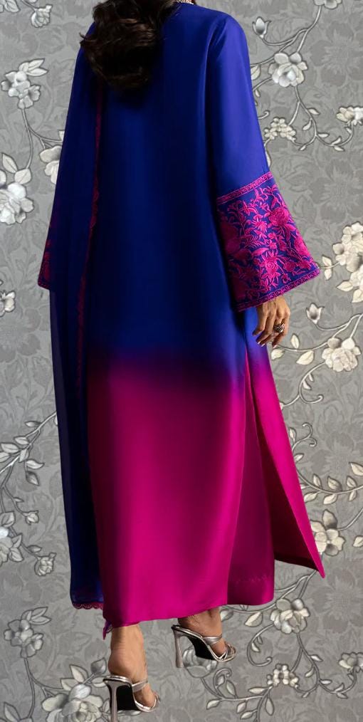 a person wearing a long, flowing dress with a gradient of blue and pink colors. The dress has a high collar and long sleeves, and the person is standing against a floral background.
