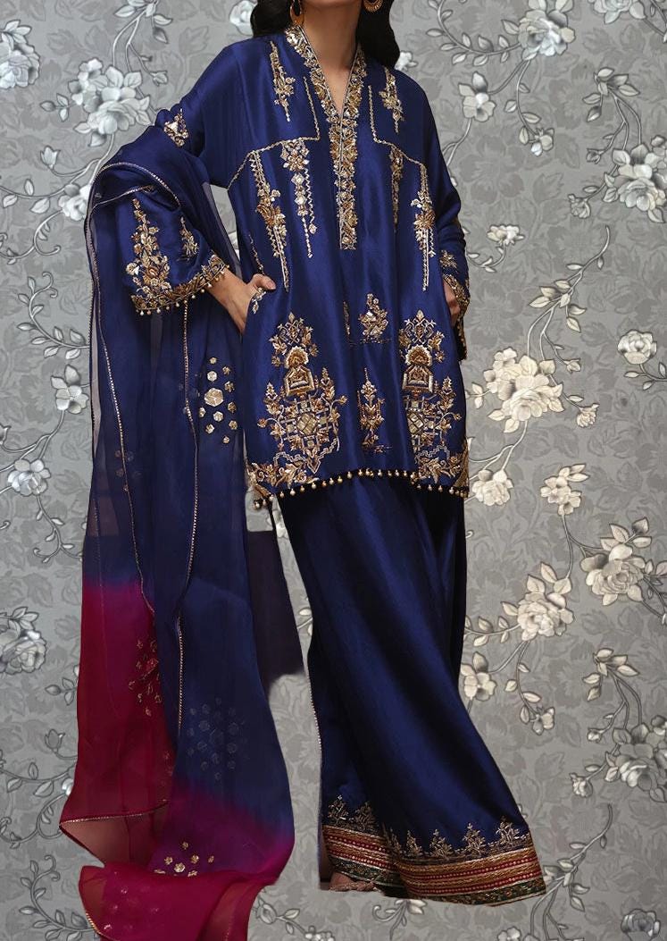 A woman wearing a blue and gold dress with intricate embroidery and a matching shawl.
