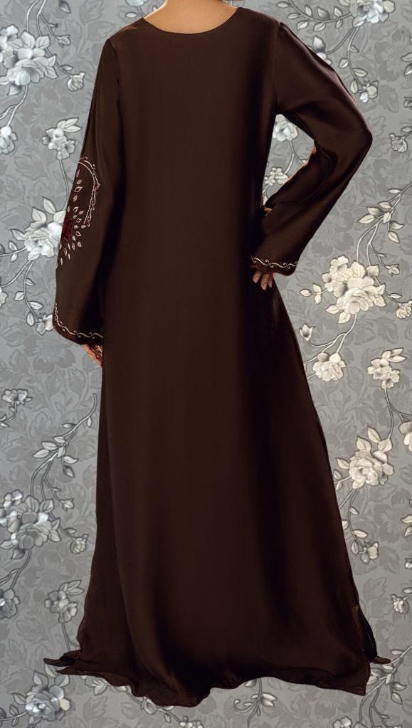 a person wearing a long brown dress with embroidered designs on the sleeves.