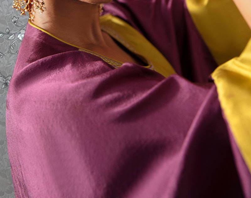 a close-up view of a person wearing a purple and gold garment, with a gold earring visible.