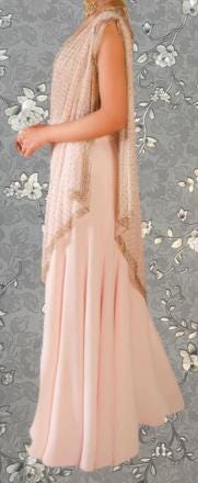 A woman wearing a long, flowing pink dress with a draped, draped-over-the-shoulder design.