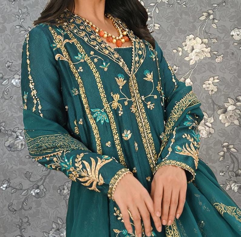 A woman wearing a green and gold embroidered dress with intricate patterns and designs.