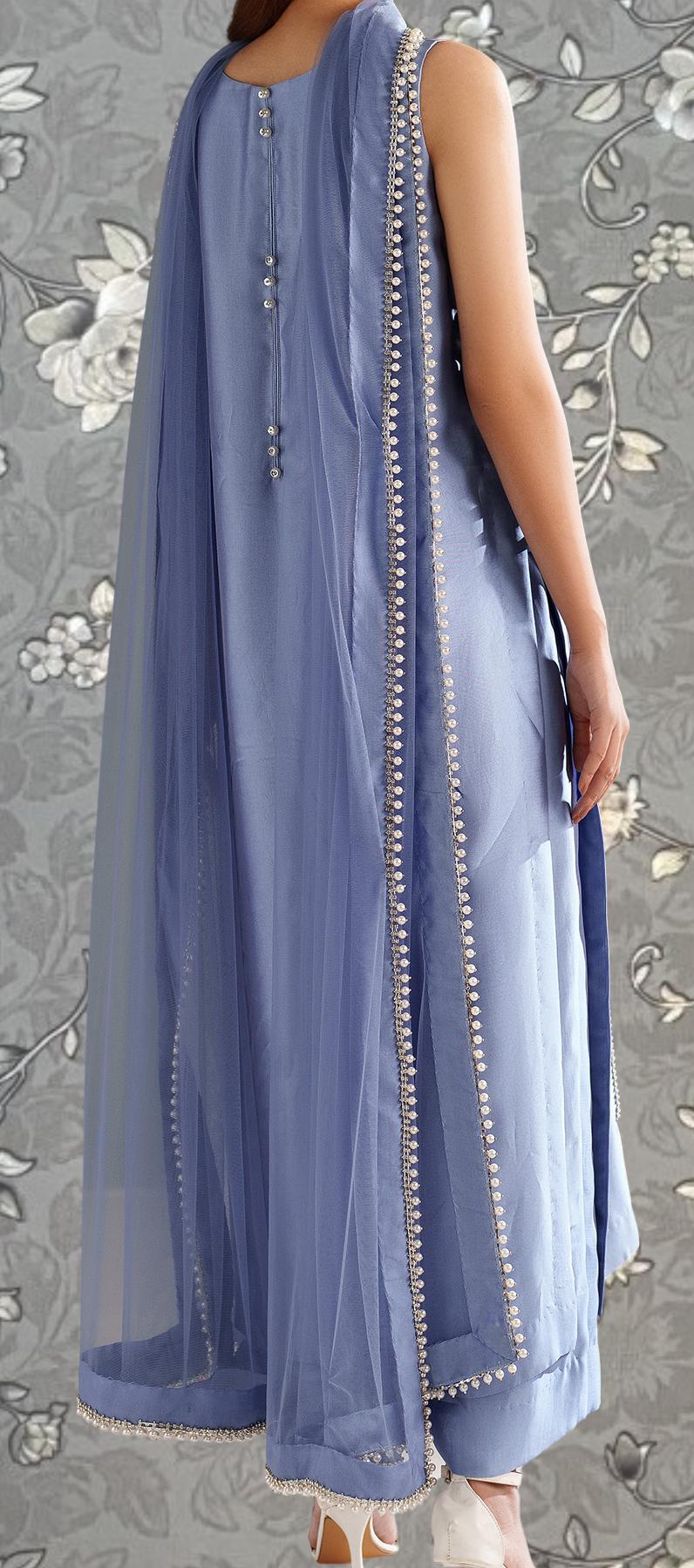 A woman wearing a long, light blue dress with a sheer, draped skirt and a matching shawl.