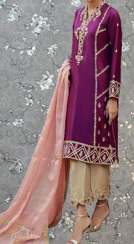 A person wearing a purple and gold dress with intricate embroidery and a matching pink shawl.