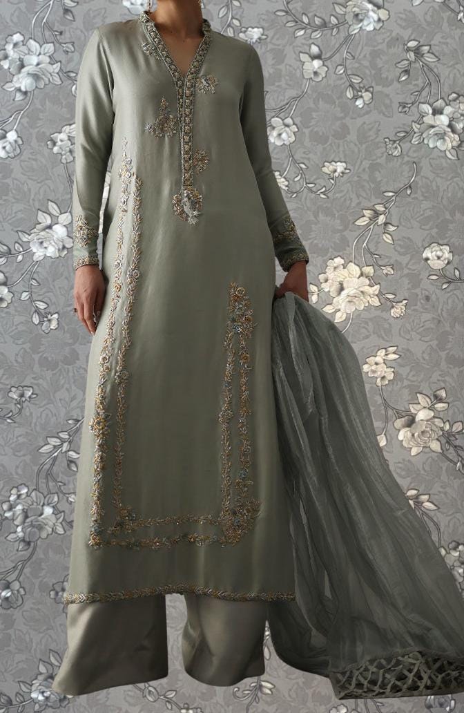 A woman wearing a long, gray dress with intricate embroidery and a matching gray shawl draped over her shoulders.
