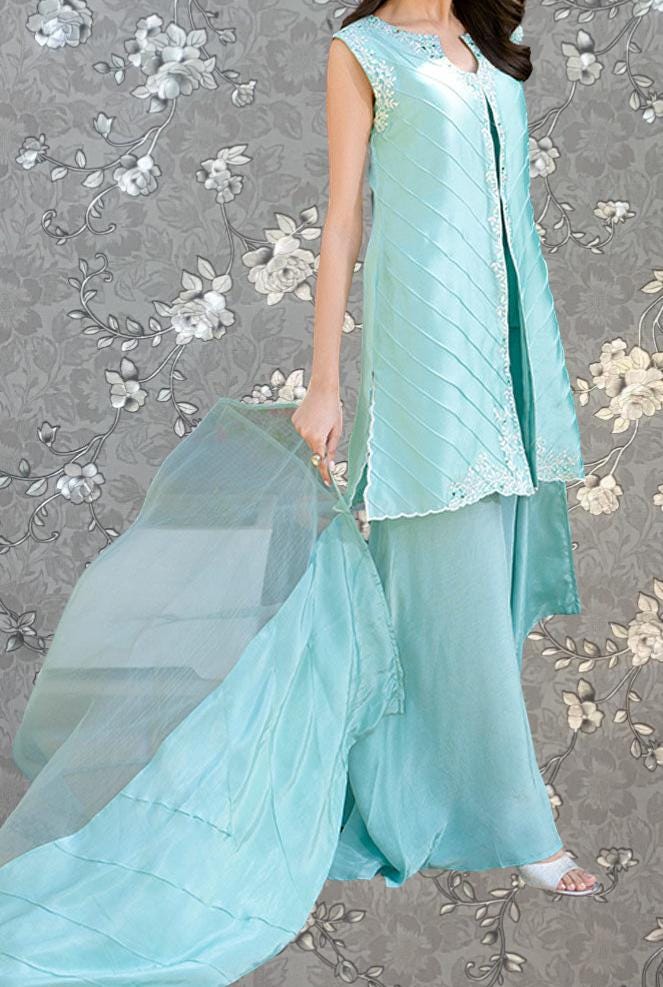 A woman wearing a mint green dress with a flowing skirt and holding a large, flowing fabric.