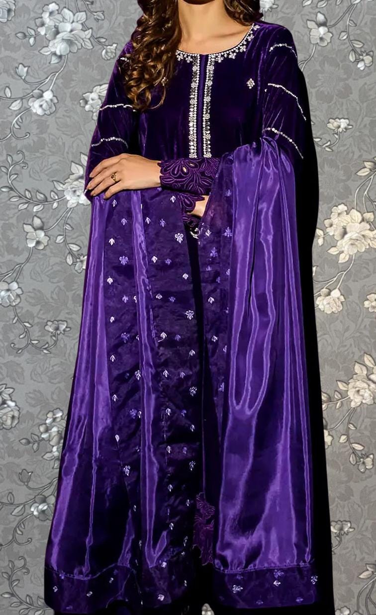 A woman wearing a long purple dress with a floral pattern and a matching purple shawl.