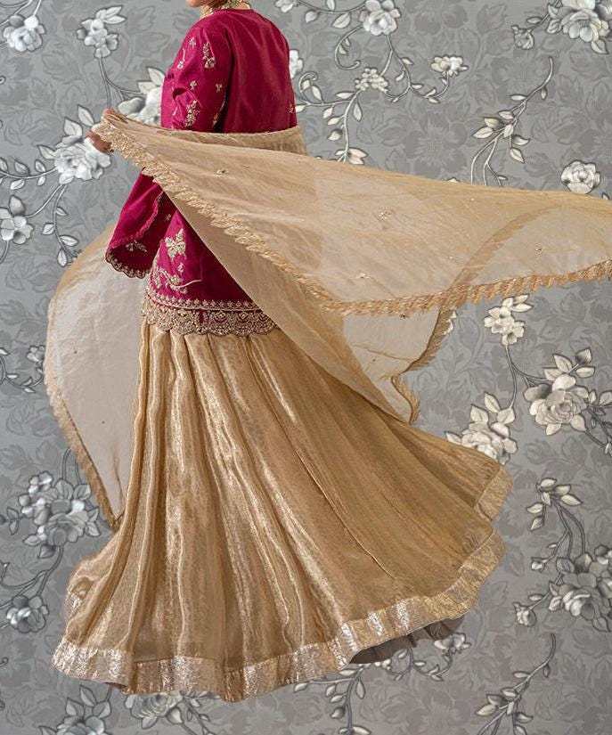 A woman wearing a red and gold dress with a flowing skirt is shown against a gray floral background.