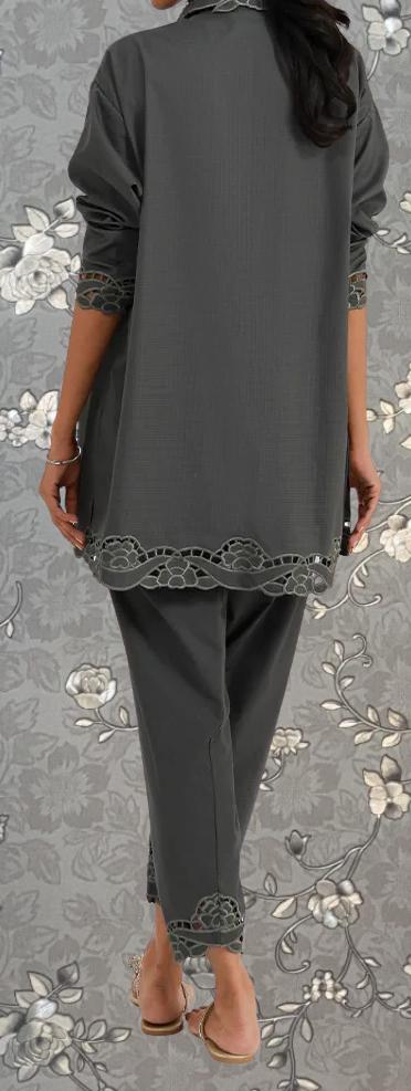 a person wearing a gray outfit with a floral pattern on the sleeves and pants, standing against a gray floral background.