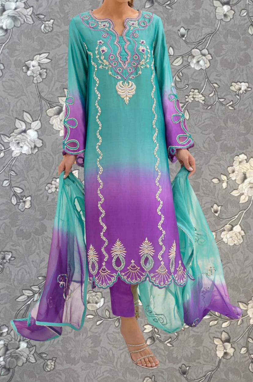 A woman wearing a long, colorful dress with intricate embroidery and patterns in shades of blue, purple, and green.