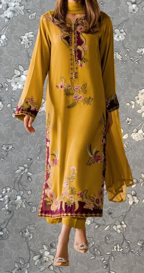 A woman wearing a long, yellow dress with intricate floral embroidery and a matching shawl.