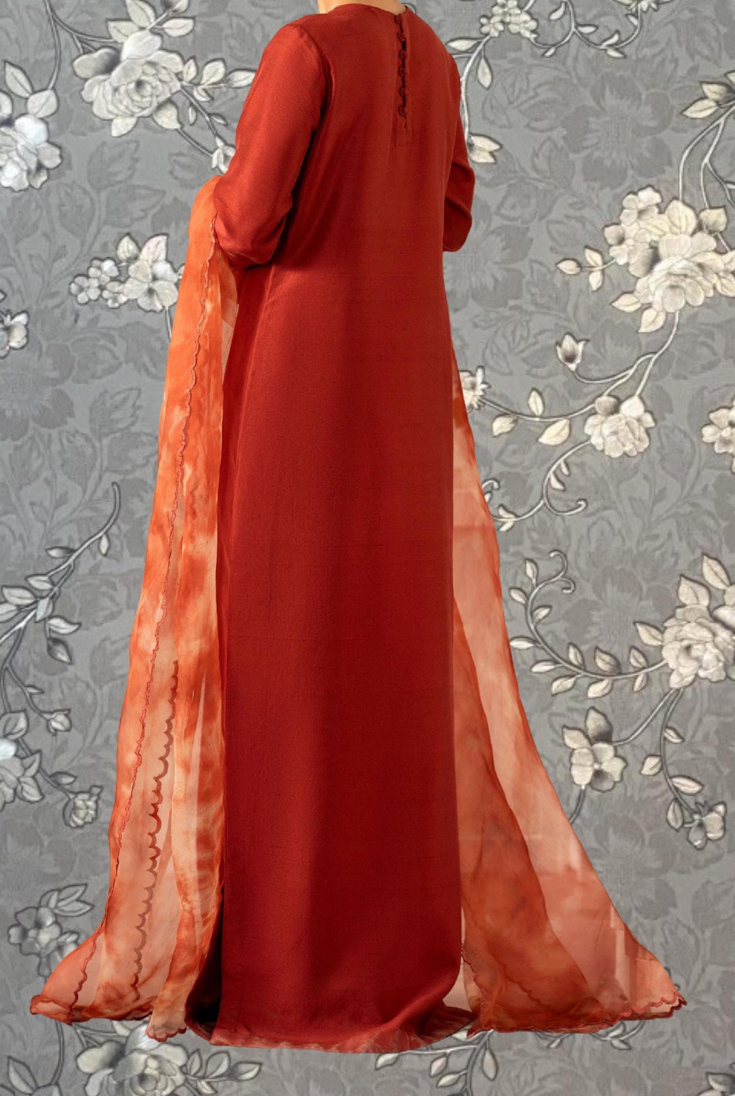 a person wearing a long red dress with a flowing orange scarf draped over the shoulder.