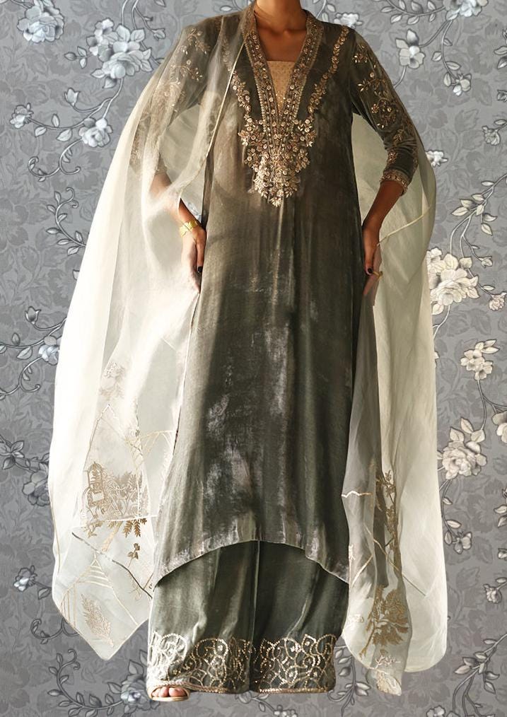 A person wearing a gray and gold dress with intricate embroidery and a sheer white shawl draped over their shoulders.