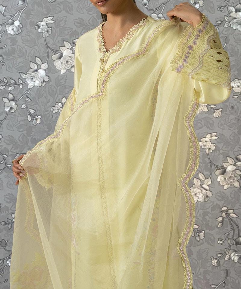 A woman wearing a yellow dress with lace trim and a sheer yellow fabric draped over her.