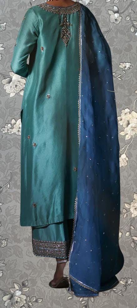 A person wearing a long, green dress with a blue shawl draped over the shoulders.