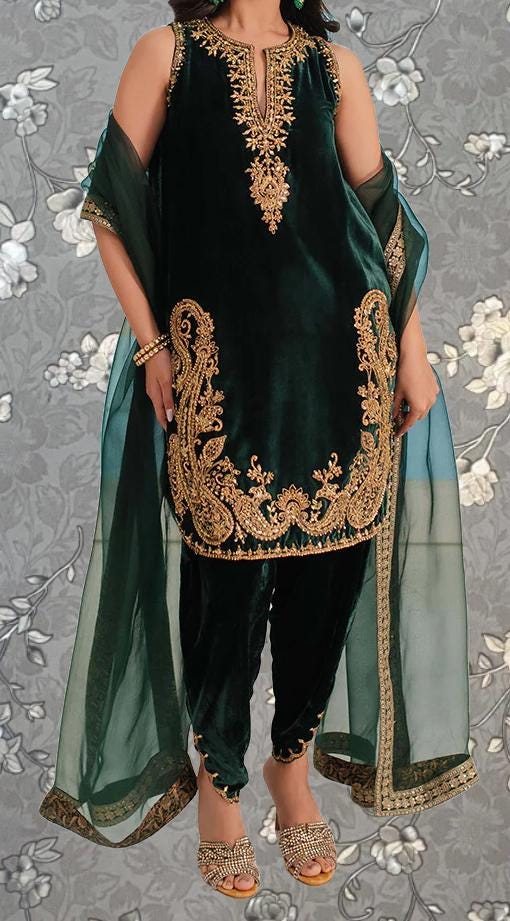 A woman wearing a green velvet dress with gold embroidery and a matching green shawl.